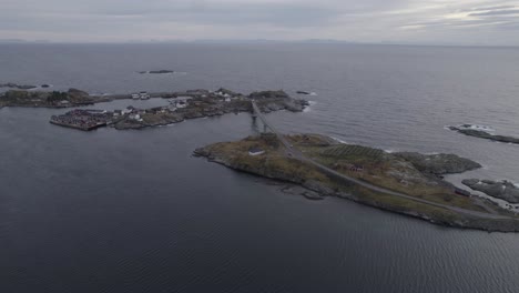 Aerial-view-of-a-car-driving-over-a-bridge-from-Toppoya-to-Hamnoy-in-cloudy-Lofoten,-Norway---tilt,-drone-shot