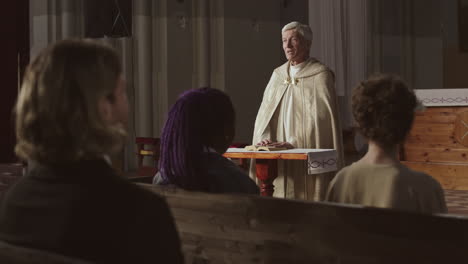 aged caucasian clergyman talking to parishioners in church