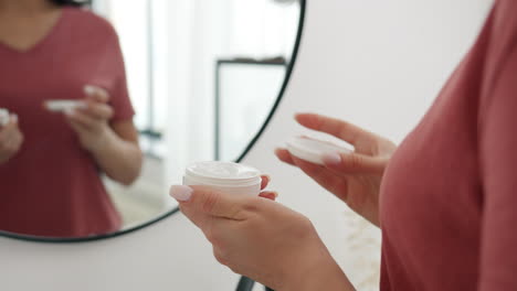 mujer aplicando crema facial frente al espejo