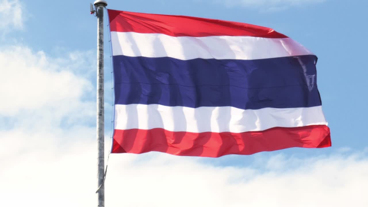 Close-up of the Thai National flag waving against the cloudy blue skies