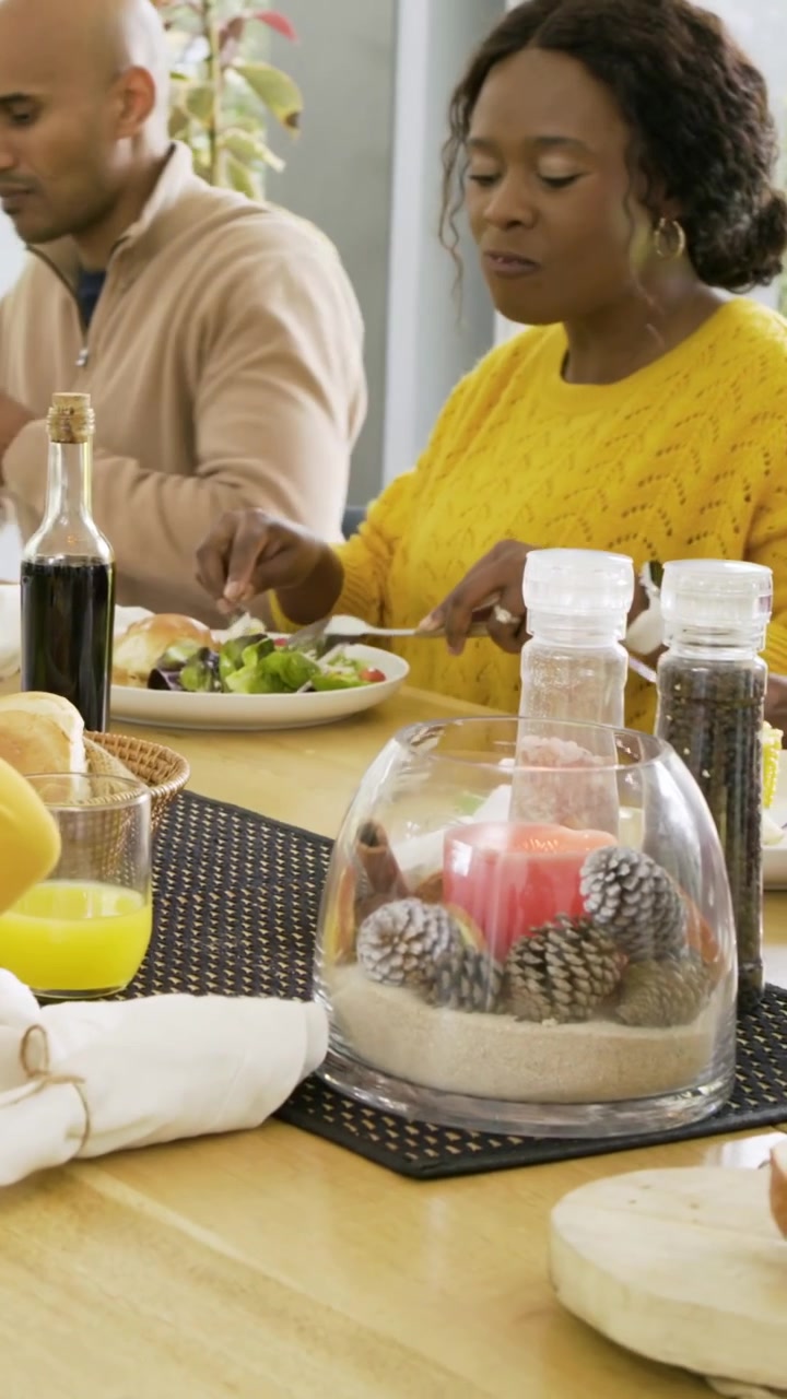 Vertical video: Reaching adult in green sweater soothing child in yellow top at table, bread shared