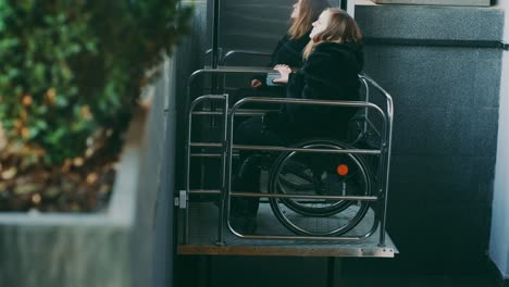 woman with disabilities in a wheelchair climbs stairs on a mechanical lift.