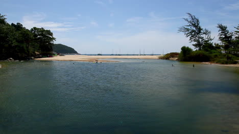 전경, 해변, 바다, 먼 배경에 있는 요트에 있는 나이 한 해변 석호의 잠긴 넓은 샷