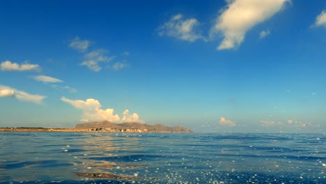 Low-angle-sea-level-view-from-sailing-boat-spraying-water-of-Favignana-island-in-Sicily,-Italy