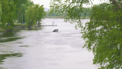 small motorized fishing boat cruises down river on breezy overcast day