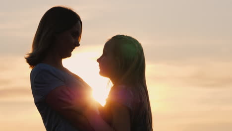 Mama-Kommuniziert-Sanft-Mit-Ihren-Tochter-Silhouetten-Bei-Sonnenuntergang