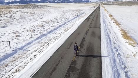 Un-Dron-De-Alto-Vuelo-Gira-Alrededor-De-Una-Mujer-Parada-En-La-Carretera