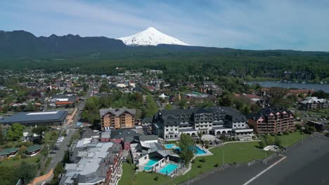 drone forward flight above pucon town with villarrica volcano and lake visible in the background