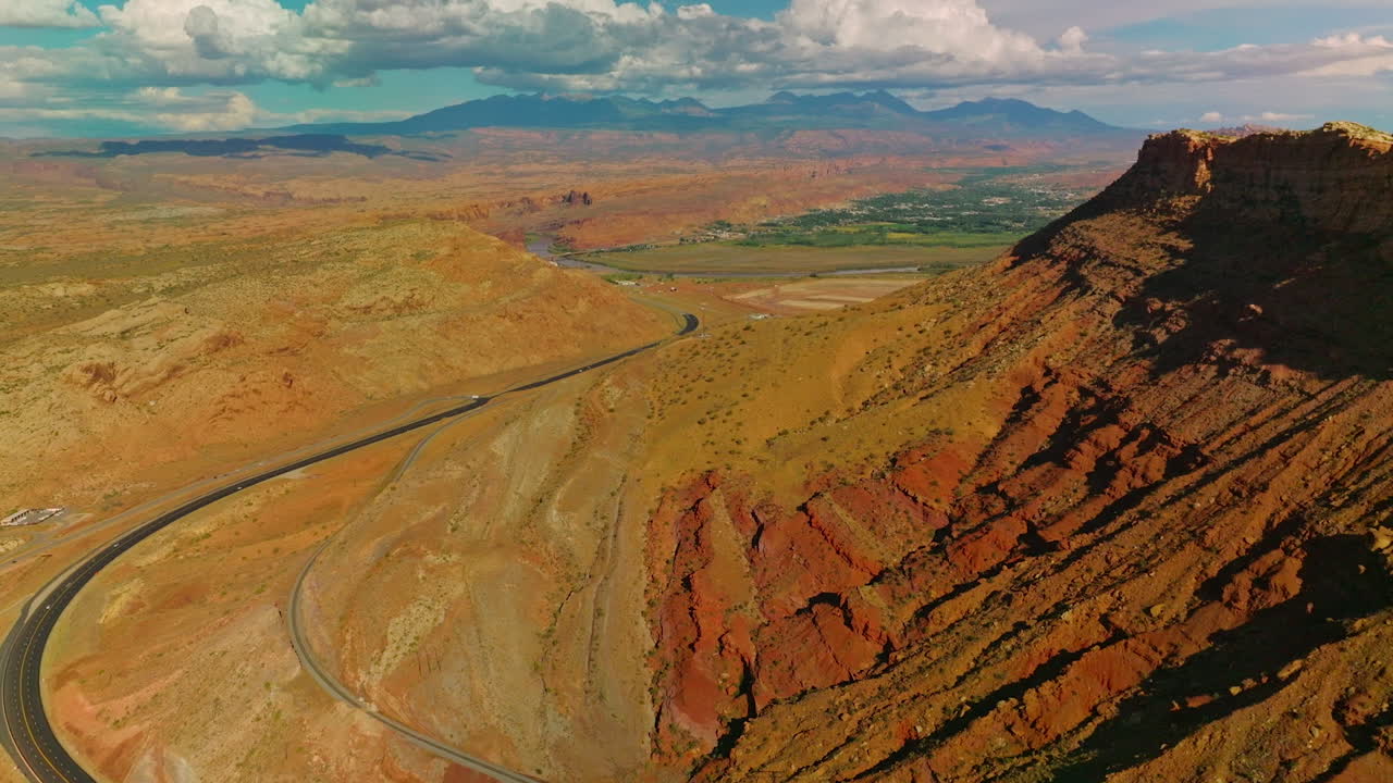 Rocks, deserts and green valleys in the national park of Utah. Drone flying over the motorway at the foot of canyon. Aerial perspective.