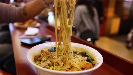 persona disfrutando de sopa de fideos con palillos