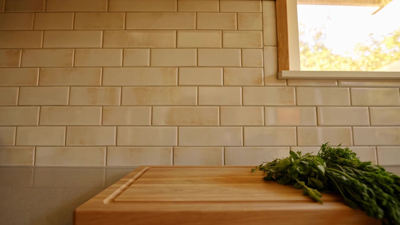 Caldo angolo interno con piastrelle in ceramica beige, finiture in legno e una finestra luminosa sulla destra che proietta la luce del sole nella stanza, con una piccola pianta che fa capolino