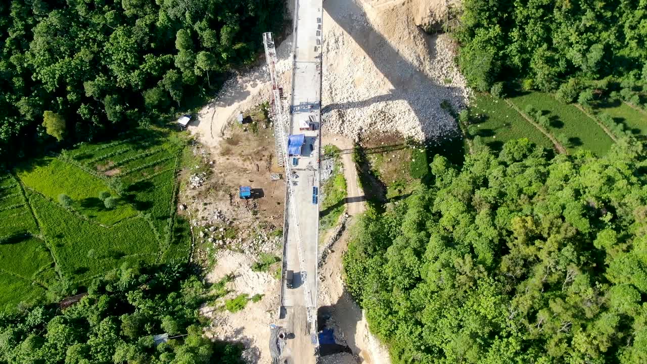 trabajadores construyendo un puente sobre el valle en el paisaje forestal, vista aérea de drones