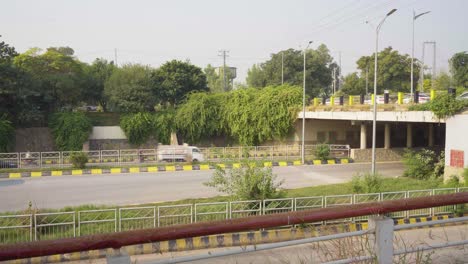 red bus driving on a road under an overpass in pakistan