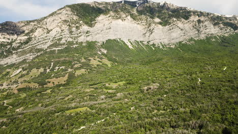 un drone descend du sommet de kyhv, révélant la route qui coupe à travers les arbres