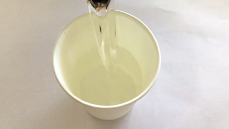 white paper cup getting filled with water, making coffee, primitive