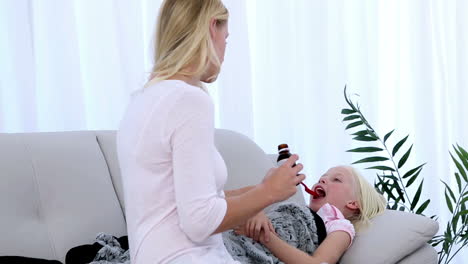 mother giving her daughter medicine on a spoon