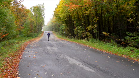 Mann-Läuft-Auf-Einer-Kleinen-Straße,-Umgeben-Von-Ahorn-Herbst-Maple-Leaf-Slowmotion