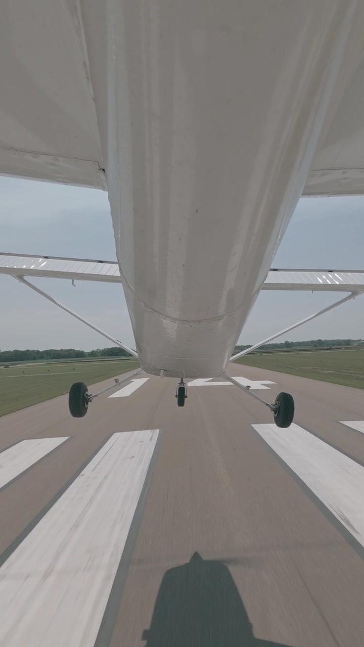 Telecamera montata sotto la fusoliera dell'aereo mostra il carrello di atterraggio e le ruote durante l'avvicinamento finale e l'atterraggio sulla pista.