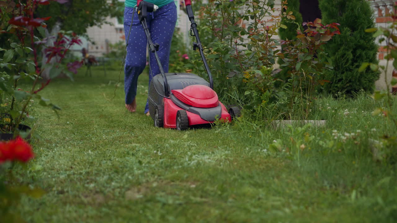 Woman running with a lawn mower in the garden. Close-up