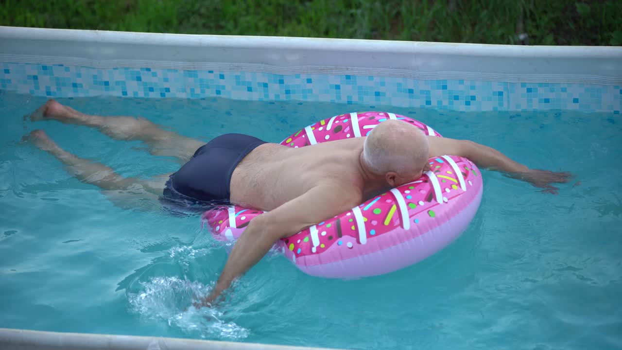 The grandfather with little granddaughter have fun in the pool. grandfather plays with the child. The family enjoy summer vacation in a swimming pool jumping, spinning, splash water.