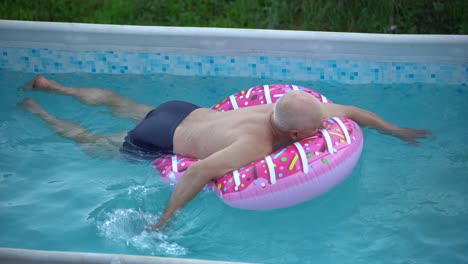 el abuelo con la nieta se divierten en la piscina. el abuelo juega con el niño. la familia disfruta de las vacaciones de verano en una piscina saltando, girando, salpicando agua.