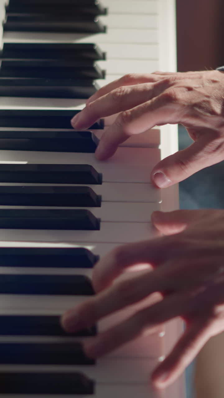 primer plano de las manos de un hombre con una camisa de manga larga azul tocando un piano blanco. momento de creación musical con detalles centrados en la interacción entre los dedos y las teclas