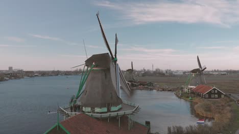 Panning-up-on-a-windmill-in-the-foreground-in-a-typical-Dutch-landscape-with-rotating-wicks-on-a-bright-day-with-blue-sky-and-other-windmills-in-the-background