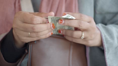 woman holding and preparing to put money in purse