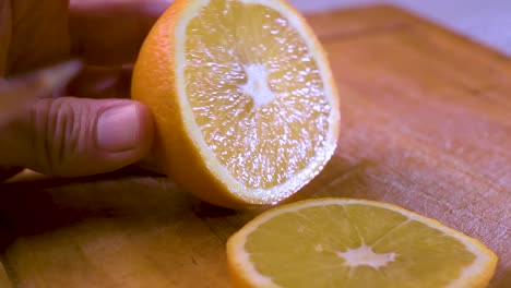 vista de la mano cortando una rodaja de naranja en una tabla de madera