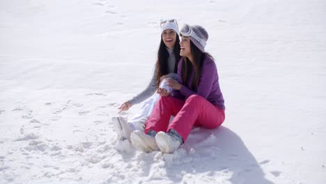 Zwei-Junge-Frauen-Sitzen-Und-Plaudern-Im-Schnee