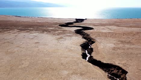 deep crack in arid landscape leading to the dead sea