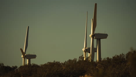 Steady-close-up-of-rotors-and-blades-of-wind-turbines-at-a-wind-farm-with-hill-in-the-foreground-near-Palm-Springs-in-the-Mojave-Desert,-California,-USA