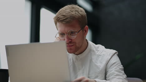 retrato de un hombre cansado y pensativo mirando la pantalla de una computadora portátil con gafas. un hombre de lluvia de ideas. resolución de problemas. pensar y trabajar