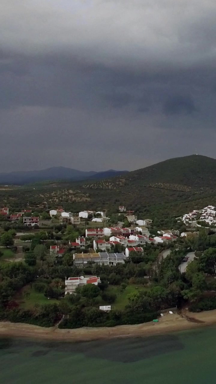 Sorvolando mare, spiaggia e cottage in una località turistica della Grecia in una giornata nuvolosa