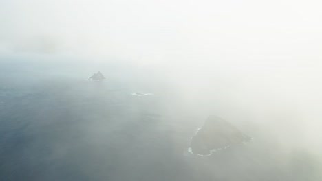 mysterious islands in blue atlantic ocean with thick clouds and mist, aerial