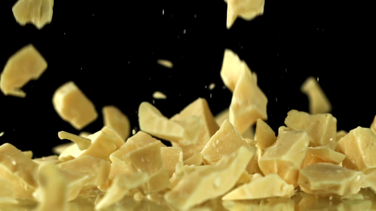White Chocolate Chunks Falling in Slow Motion on Black Background