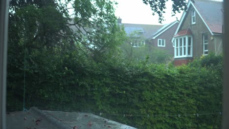 Heavy-Rain-Falling-on-Roof-with-Garden-Background