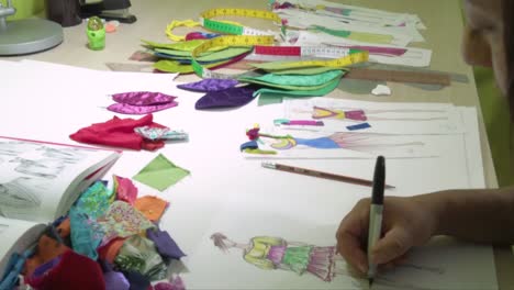 latin fashion designer drawing new ideas for dresses using color markers