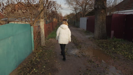 woman walking down a rural street in autumn