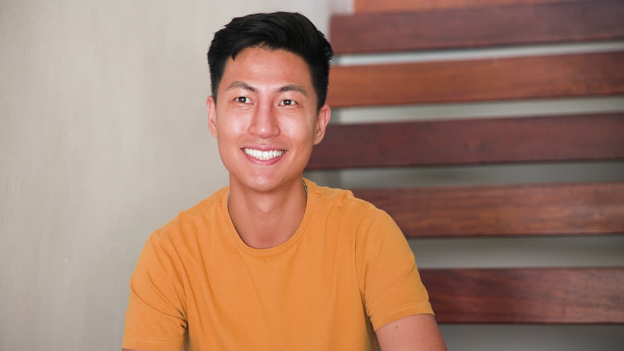 Man enjoying coffee at home, sitting on stairs, wearing casual yellow shirt, copy space