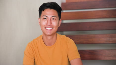 man enjoying coffee at home, sitting on stairs, wearing casual yellow shirt, copy space