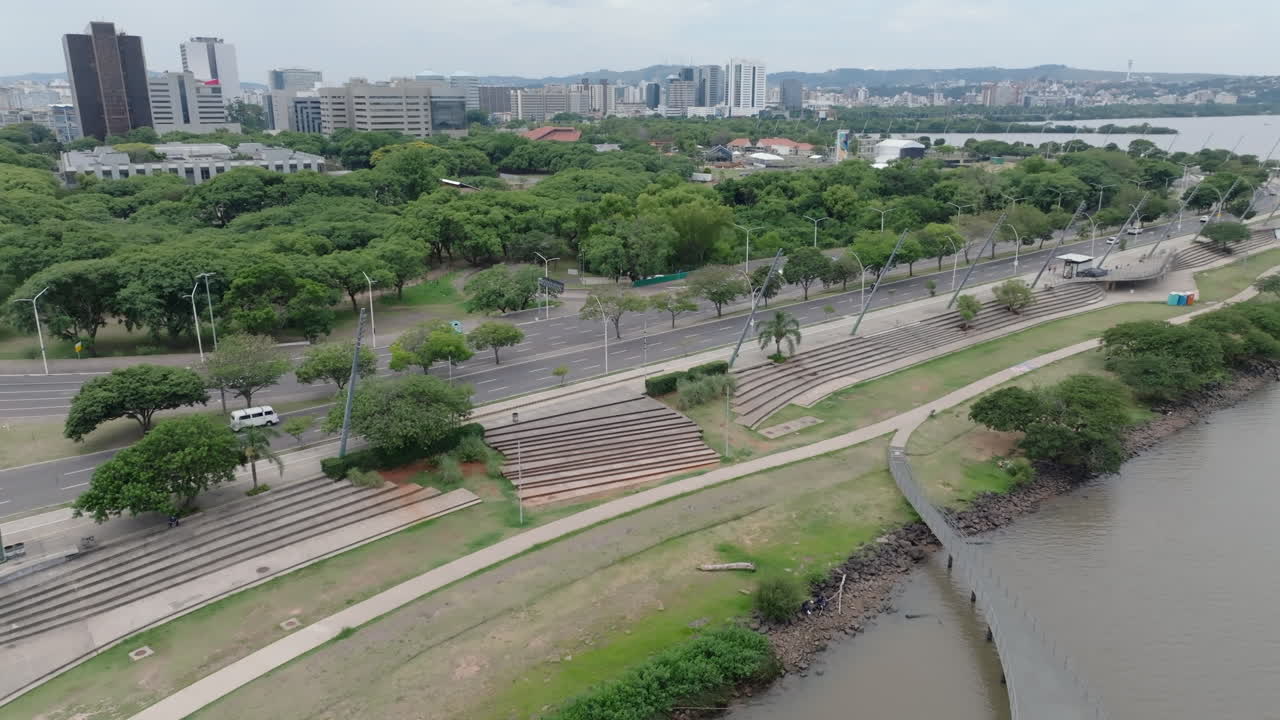 Passerella sul lungomare di Porto Alegre e traffico di Beira Rio Avenue ripresi in volo aereo laterale parallelo. Infrastrutture urbane con cielo nuvoloso. Registrato in video 4K D-Log a 10 bit