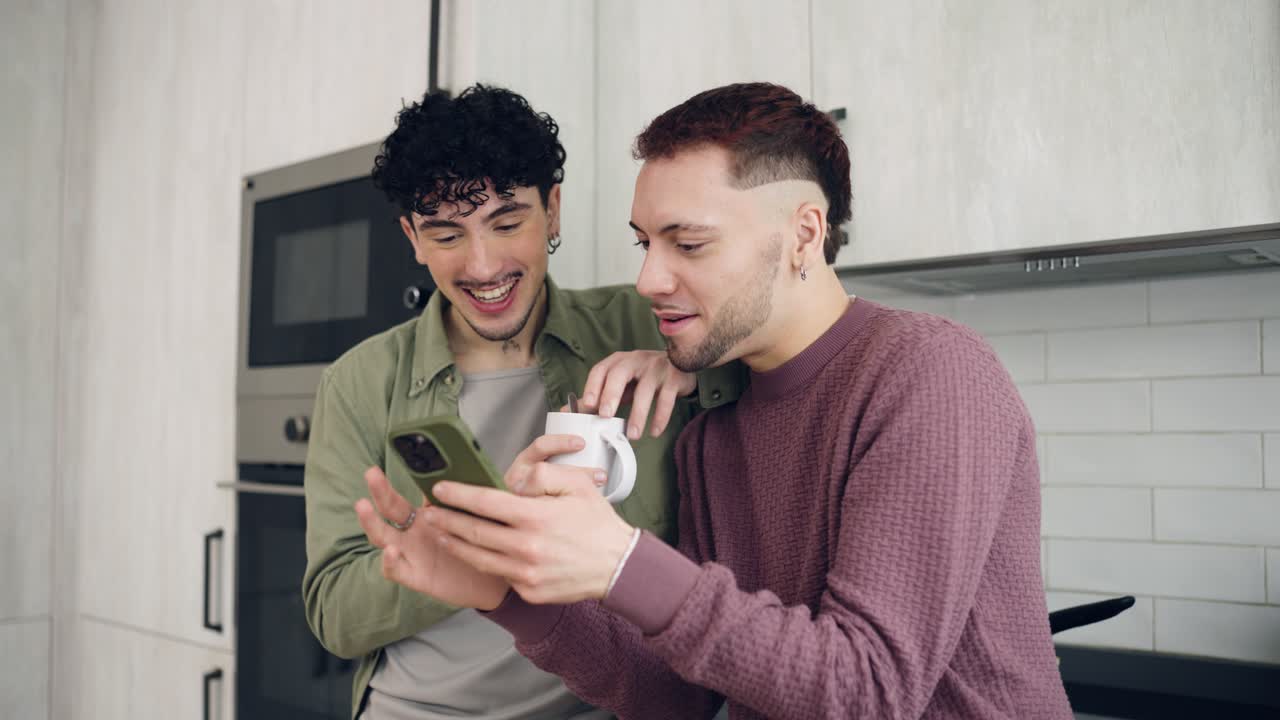 Jovens Felizes Rindo e Compartilhando Conteúdo no Smartphone na Cozinha