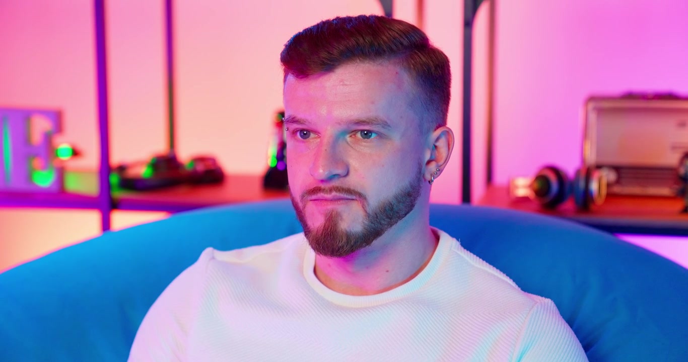 Giovane uomo concentrato seduto in una stanza illuminata al neon