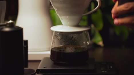 black coffee slowly drip into glass carafe while barista warm up cup