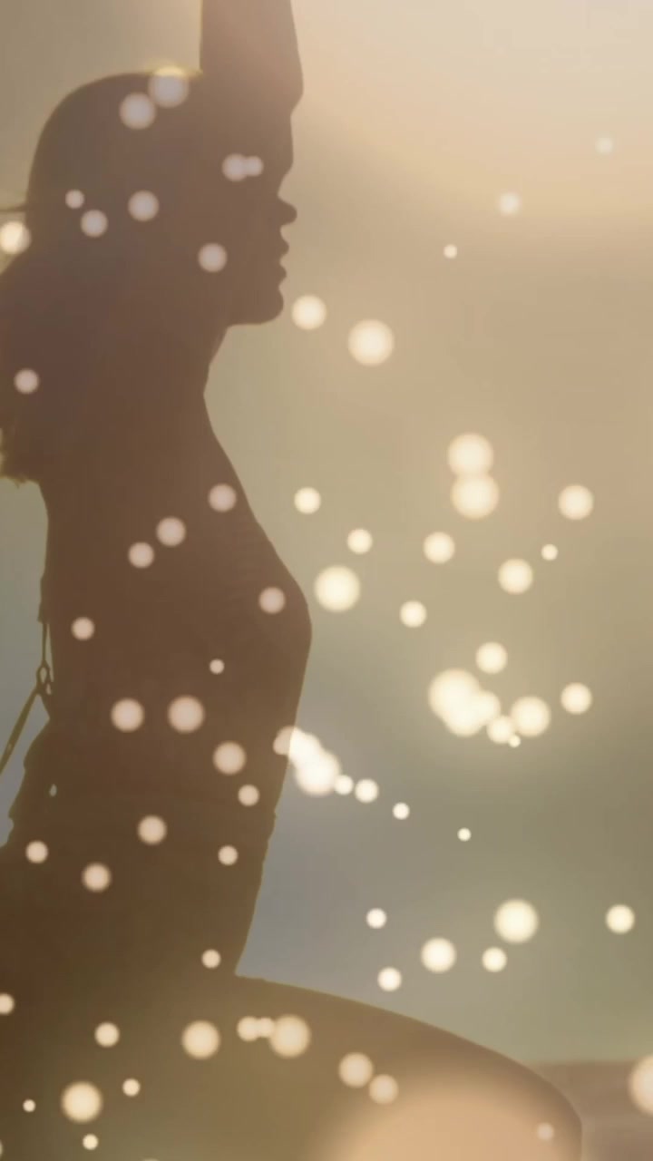 Golden glowing spots moving against woman performing yoga background