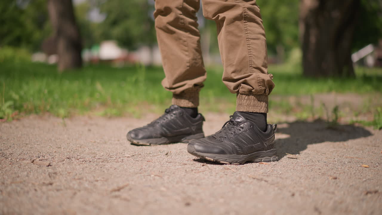 Sneakers With Deliberate Steps, Close View Of Sports Shoes On Sandy Ground Showing Precise Foot Positioning, Detailed Image Of Athletic Footwear And Foot Movement On Gravelly Outdoor Surface