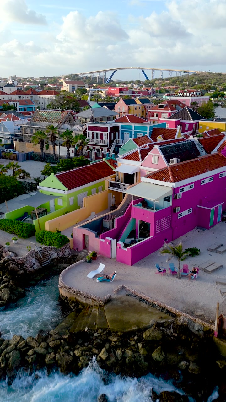 Vertical HD aerial shot of sunset over Pietermaai district with waterfront homes and warm Caribbean city light.
