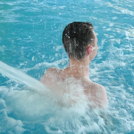 boy under the jet of water in the pool