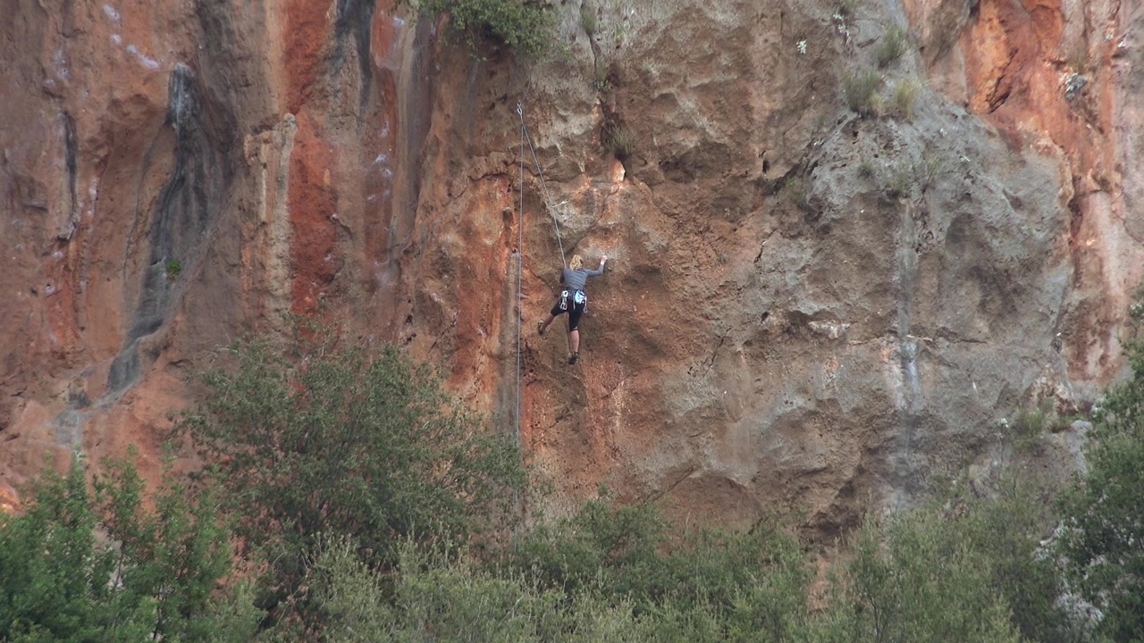 Rock Climber Ascending a Steep Limestone Cliff Face